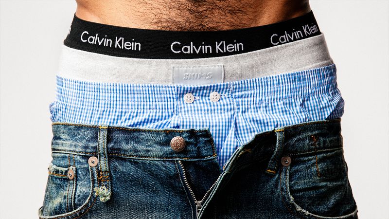 A man wearing three pairs of underwear form Calvin Klein, Skims, and Derek Rose.