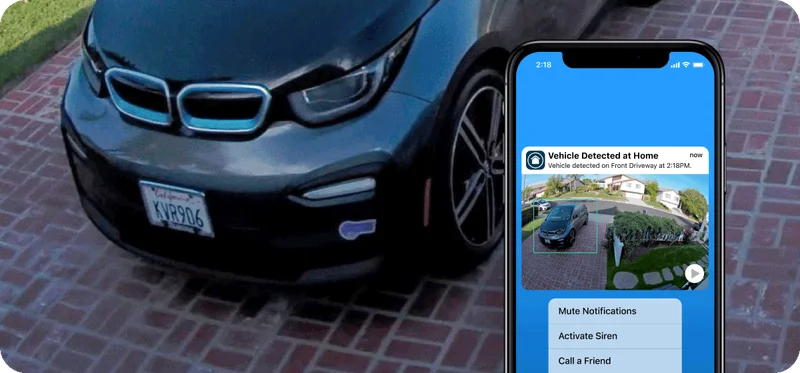 A phone showing a simulated screen image of an Arlo Secure notification. The background shows a simulation of a zoomed image to identify a license plate on a vehicle.