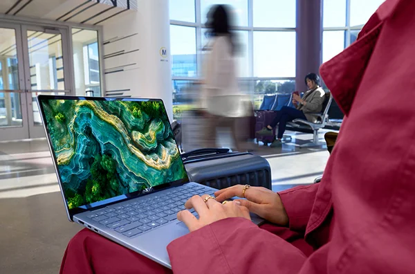 Person using Dell 14 Plus laptop in transit station.