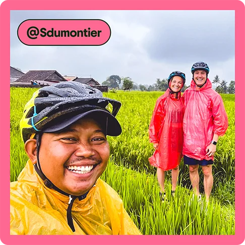 Image description: A tour guide taking a selfie with two travelers in the background posing in a rice paddy, photo taken by @Sdumontier