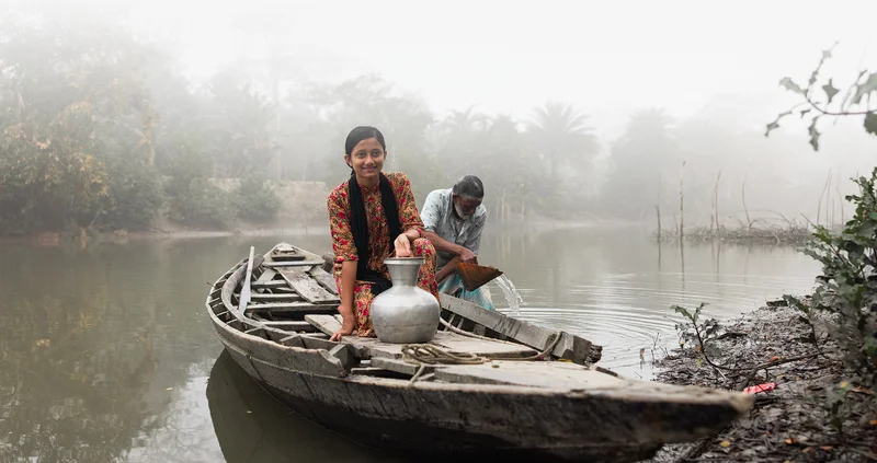 Jui sits in a boat on a foggy river.