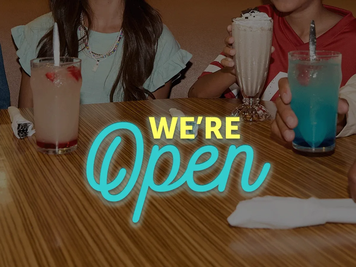 We’re Open text is centered on a soft-focus image of a tightly cropped photo of young people with beverages at an IHOP booth.
