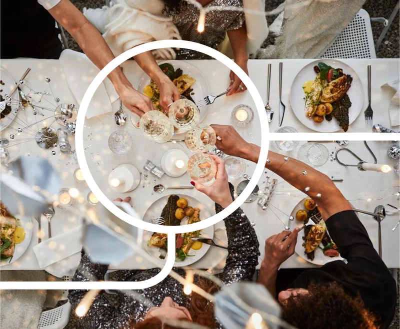 A birds-eye view of festive dining people. The people sitting at the table are toasting with glasses.