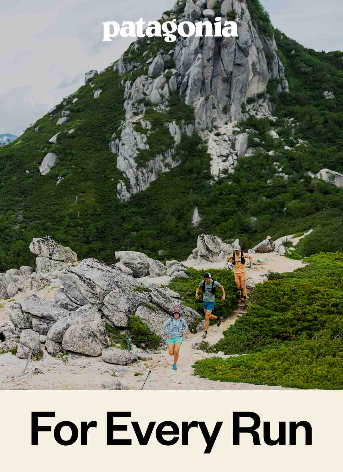 Three people running down a trail in the mountains.