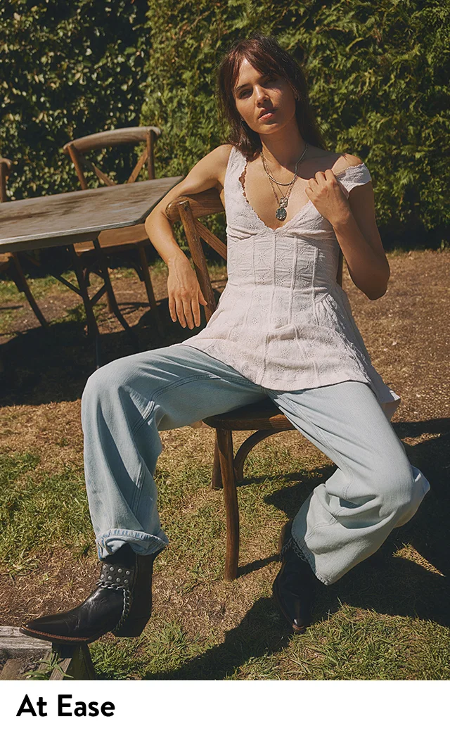 A woman wearing a white tank, jeans and cowboy boots.