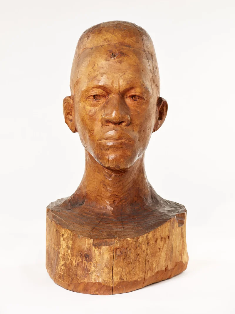 Carved wooden bust depicting a man’s solemn, angular face