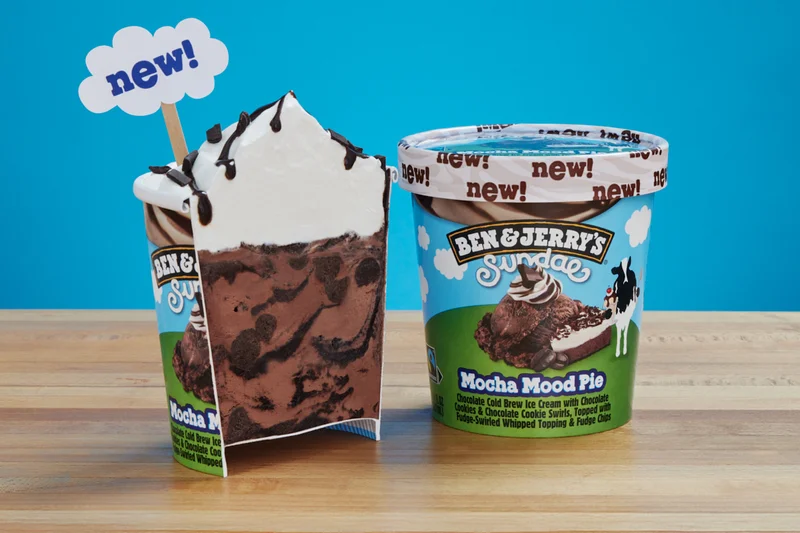 Pint of Ben & Jerry's Mocha Mood Pie Sundae ice cream cut in half so you can see the whipped topping and chunks and swirls.