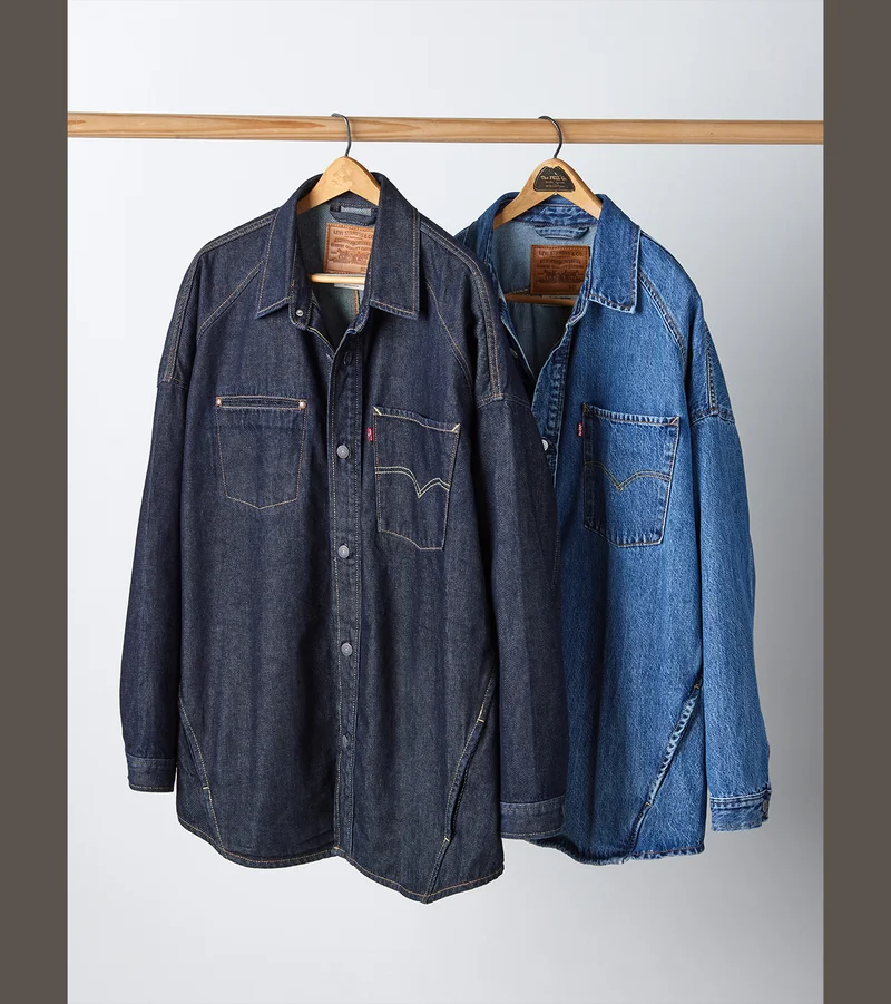 A dark wash and medium wash western shirt hanging on a rack