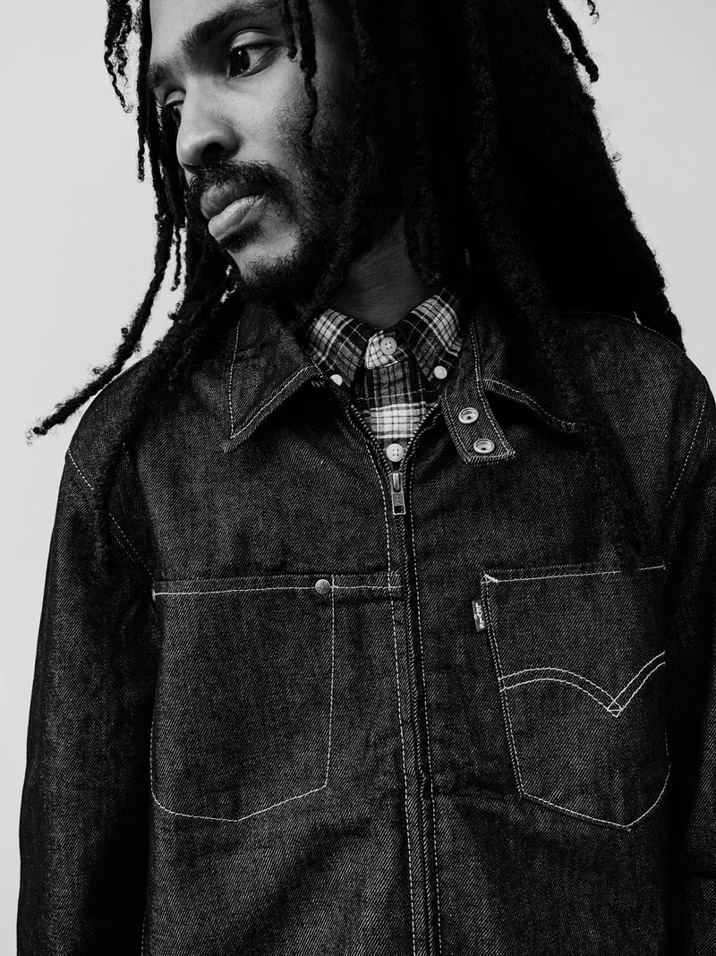 Black and white image of man wearing a trucker jacket.