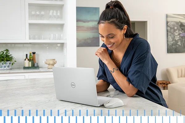 women in kitchen laughing at laptop in blue shirt