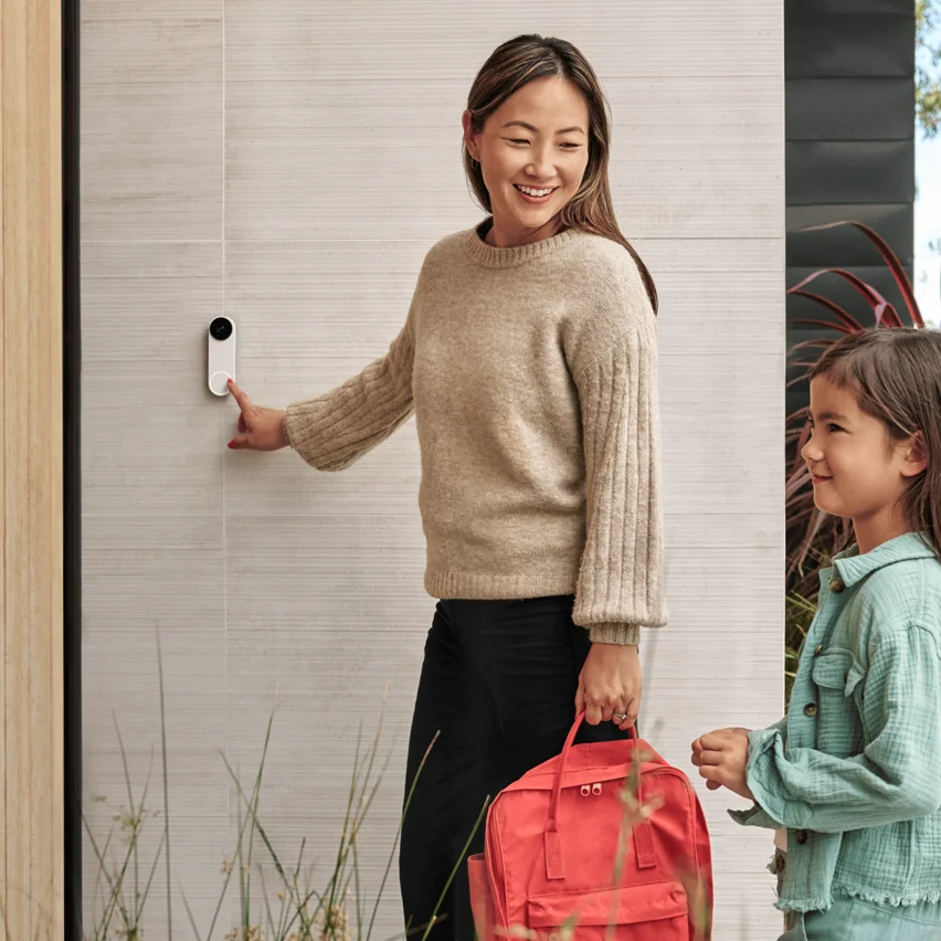 Woman with a red backpack and child pressing a smart doorbell.