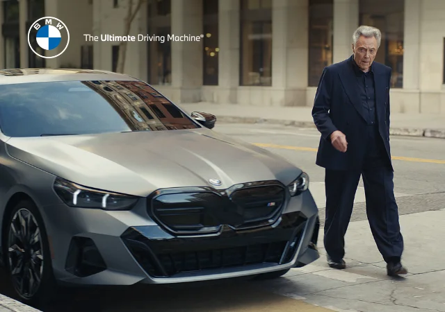 Christopher Walking approaching from the BMW i5 sedan. BMW. The Ultimate Driving Machine.