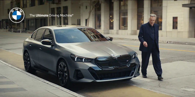 Christopher Walking approaching from the BMW i5 sedan. BMW. The Ultimate Driving Machine.