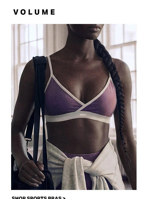 Woman with a braid models a purple sports bra with white trim, carrying a gym bag. Explore our comfortable activewear and sports bra collection.
