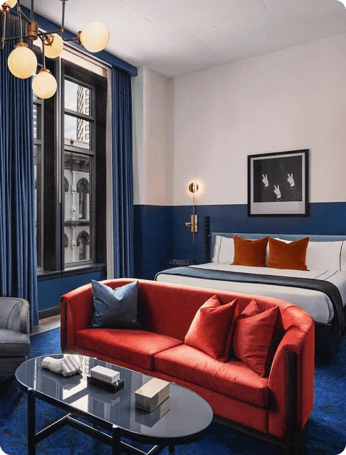 Image Description: An art-deco inspired hotel room with a jewel red couch and royal blue carpeting