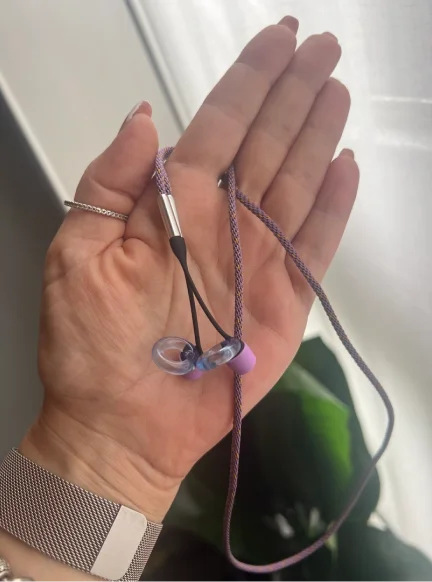 A hand holding a set of Loop Engage Kids earplugs connected by the Loop Link cord.