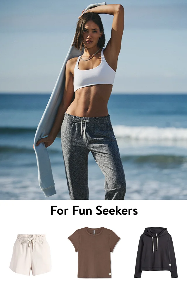 A woman standing on the beach in a sports bra and joggers. A hoodie, tee and shorts.