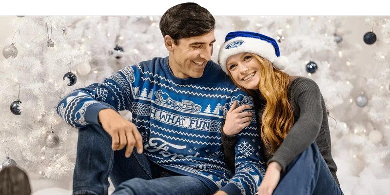Two people sitting in front of a white holiday tree in Ford holiday merchandise