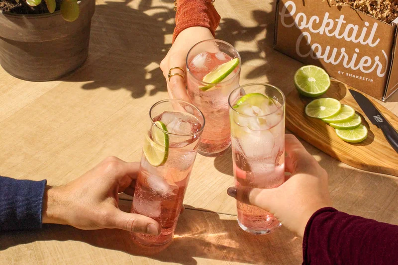 Three friends clinking cocktails to celebrate a graduation