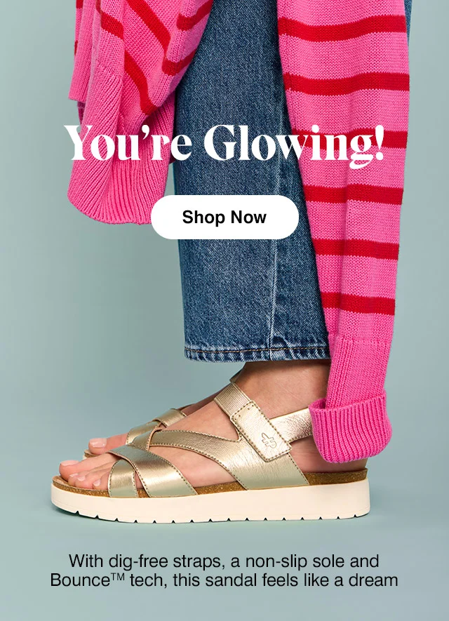 Woman in pink-and-red striped sweater, blue jeans and the Savoy sandal in metallic champagne. Shop Now.