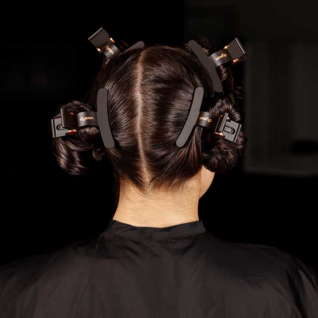 A close-up of the back of a model, with a centre parting and the Dyson Wide hair clips sectioning hair.
