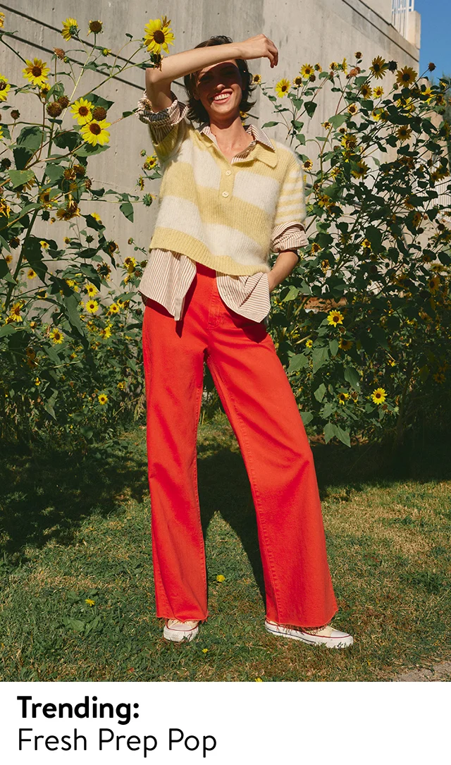 A woman wearing a yellow striped knit top over a striped button-up shirt with red pants.