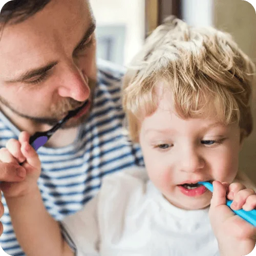 a toddler brushing his teeth with dad a toddler brushing his teeth with dad