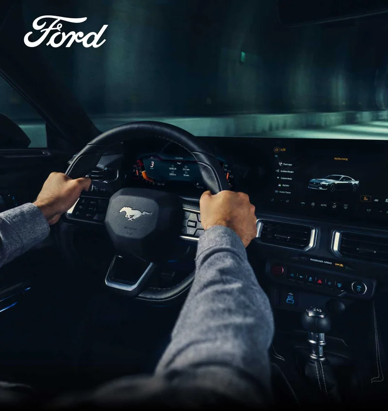 Someone gripping the wheel of a Ford Mustang.