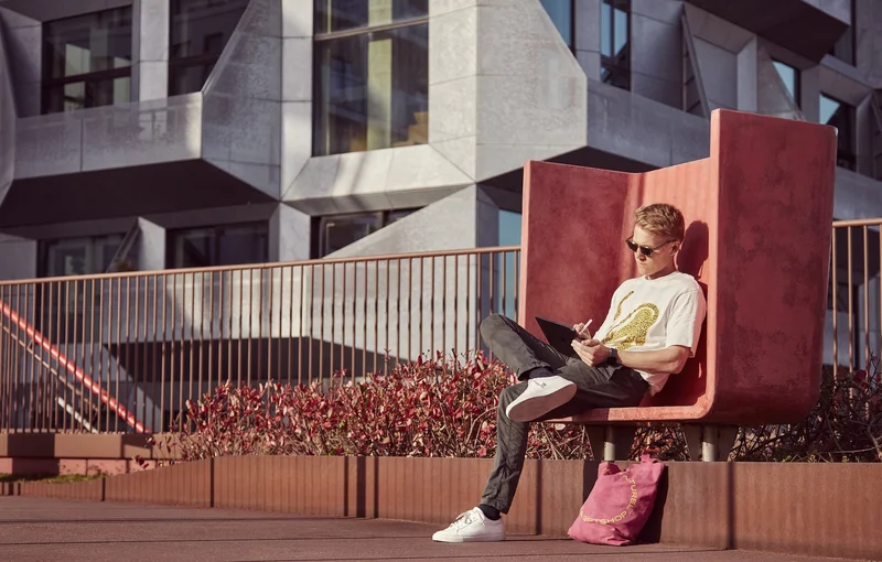 A man sits outside working on an iPad with an Apple Pencil.