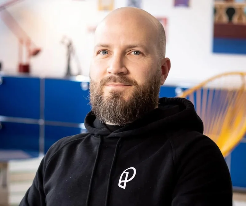 A man smiling at the camera, wearing a Paperlike hoodie.