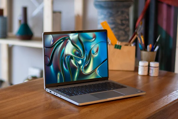 A Dell laptop opened and sitting in a pottery studio.