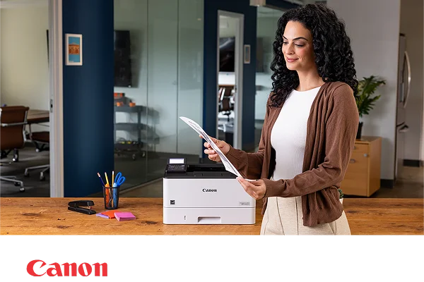 A person in a modern office admiring a document next to a Canon laser printer.