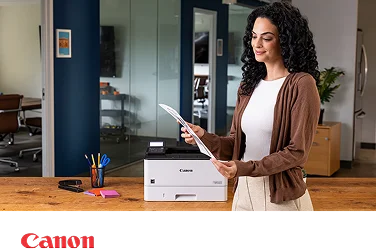 A person in a modern office admiring a document next to a Canon laser printer.