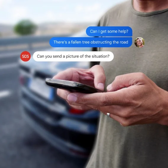 Photo of a person’s hands using a phone to text. Google Messages chat bubbles are overlaid on the photo. The first reads “can I get some help?”; the second reads, “there’s a fallen tree obstructing the road.” A third text from “SOS” reads: “Can you send a picture of the situation?”