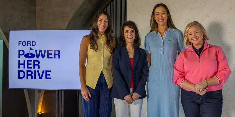 A promotional image for the Ford Power Her Drive campaign, featuring professional golfer Michelle Wie West smiling and standing on a stage next to various women involved with the program.