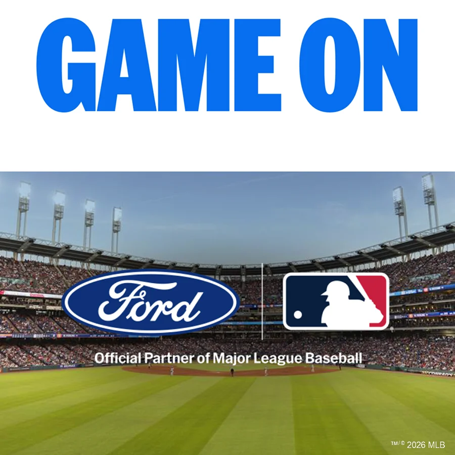 A wide view of a baseball stadium filled with fans, featuring the Ford logo and Major League Baseball logo centered above the field, alongside the message ’Official Partner of Major League Baseball’.