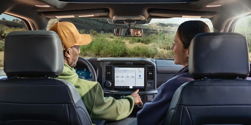 A couple shares a moment on the road in their Ford F‑150® truck, using the large center screen to plan the next leg of their journey