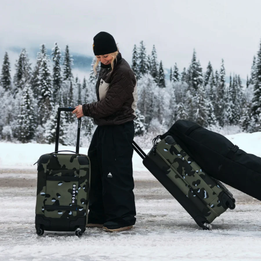 Burton Team Rider, Ylfa Runarsdottir, on a snow covered road with the 4-Wheel Flight Deck 38L, 4-Wheel Double Deck 86L, and a wheelie snowboard bag.
