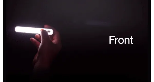 Close-up of a hand holding a sleek, glowing smart light labeled 'Front' against a dark background.
