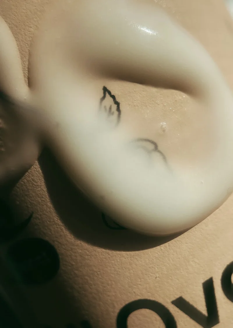 A close up of lotion on a pink metal bottle.