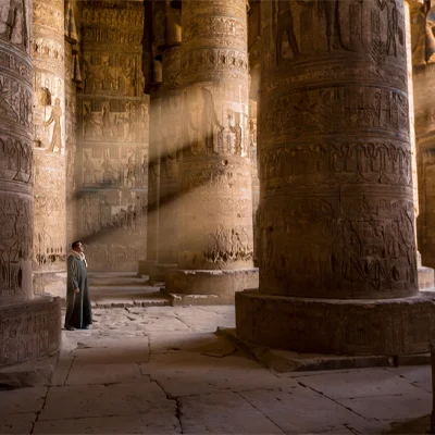 A guard at Abydos watches light filter amid the temple columns. Located in a remote valley, the ancient Egyptian burial and worship site is threatened by looting and urban development.