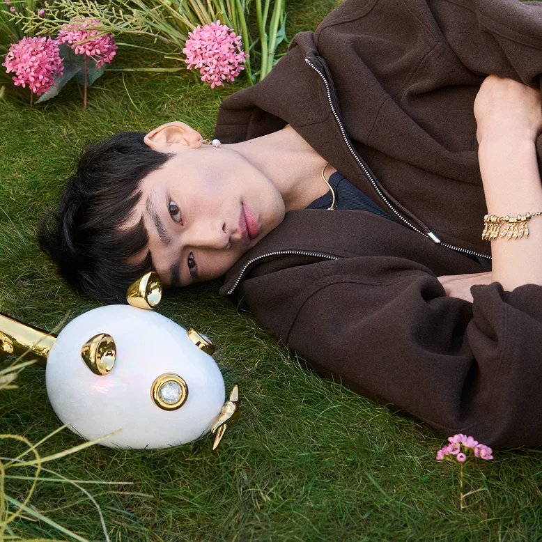 Model lies on the grass beside a super-sized mouse charm