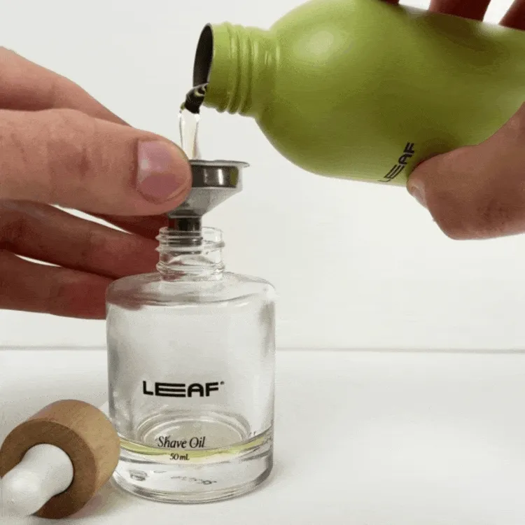moving image of someone refilling a shave oil bottle with a funnel