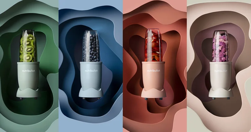 Stylized group of 4 nutribullet blenders in different colors filled with fruit and veggies of corresponding colors.