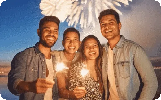 Image of 4 people holding sparklers with fireworks in background