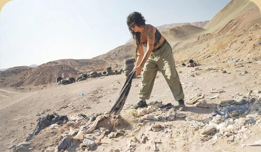 A person pulls on an old piece of clothing that’s buried in the desert.