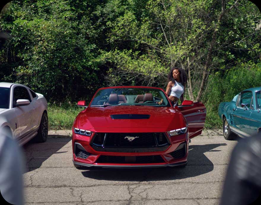 A woman standing by a 2024 Ford Mustang.