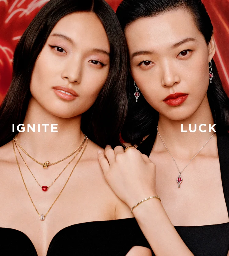 Two women wearing Pandora jewelry with red fireworks in the background Two women wearing Pandora jewelry with red fireworks in the background