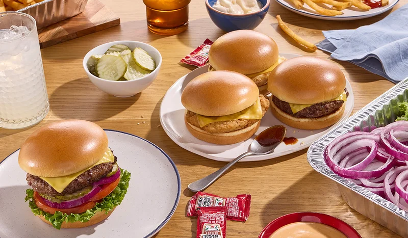 An assortment of IHOP Steakburgers and Chicken Sandwiches, along with a catering tray filled with sliced onions and lettuce