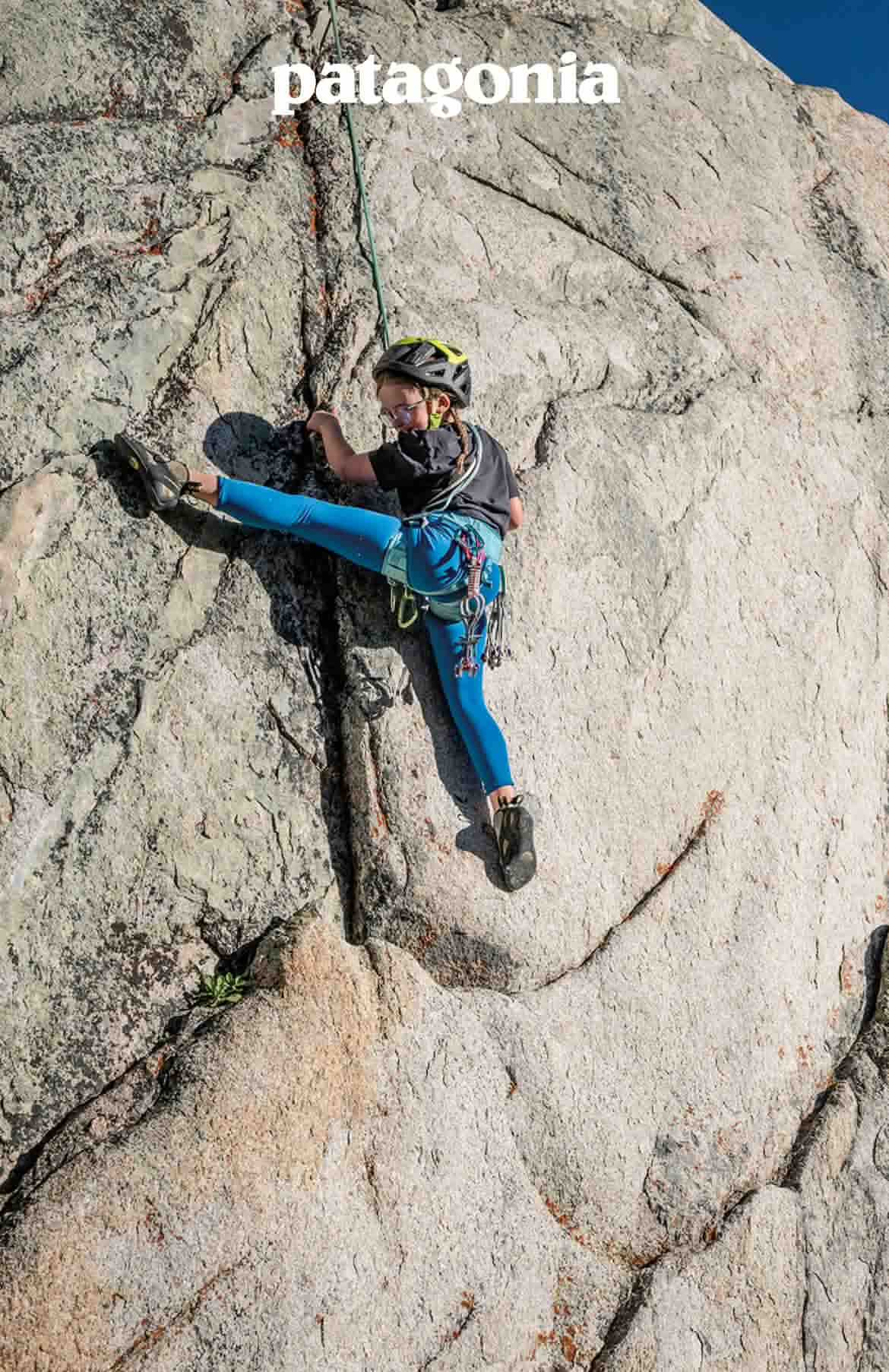 Patagonia. A kid high steps while rock climbing.